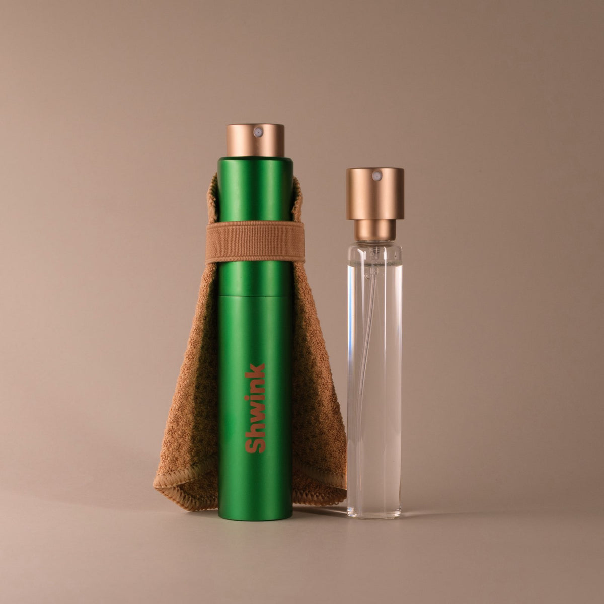 Shwink on-the-go stain spray in matte with stain-lifting cape and refillable glass insert bottle on a warm taupe background — portable stain remover with refill.