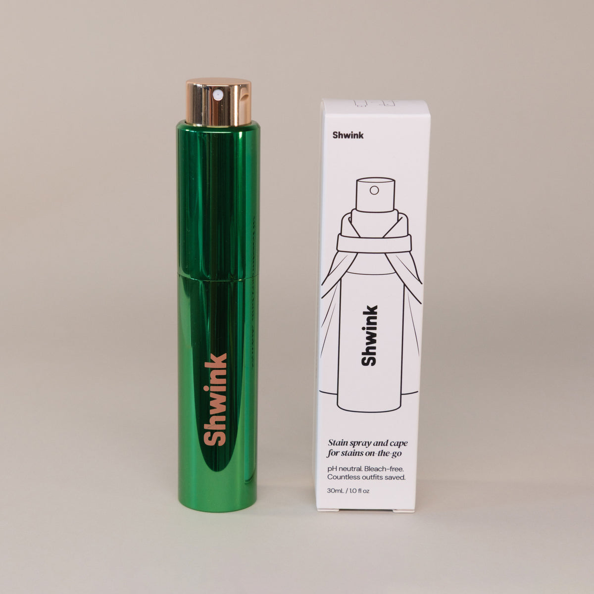 Shwink on-the-go stain spray (glossy green aluminium cylindrical tube) and white product box with black ink. 